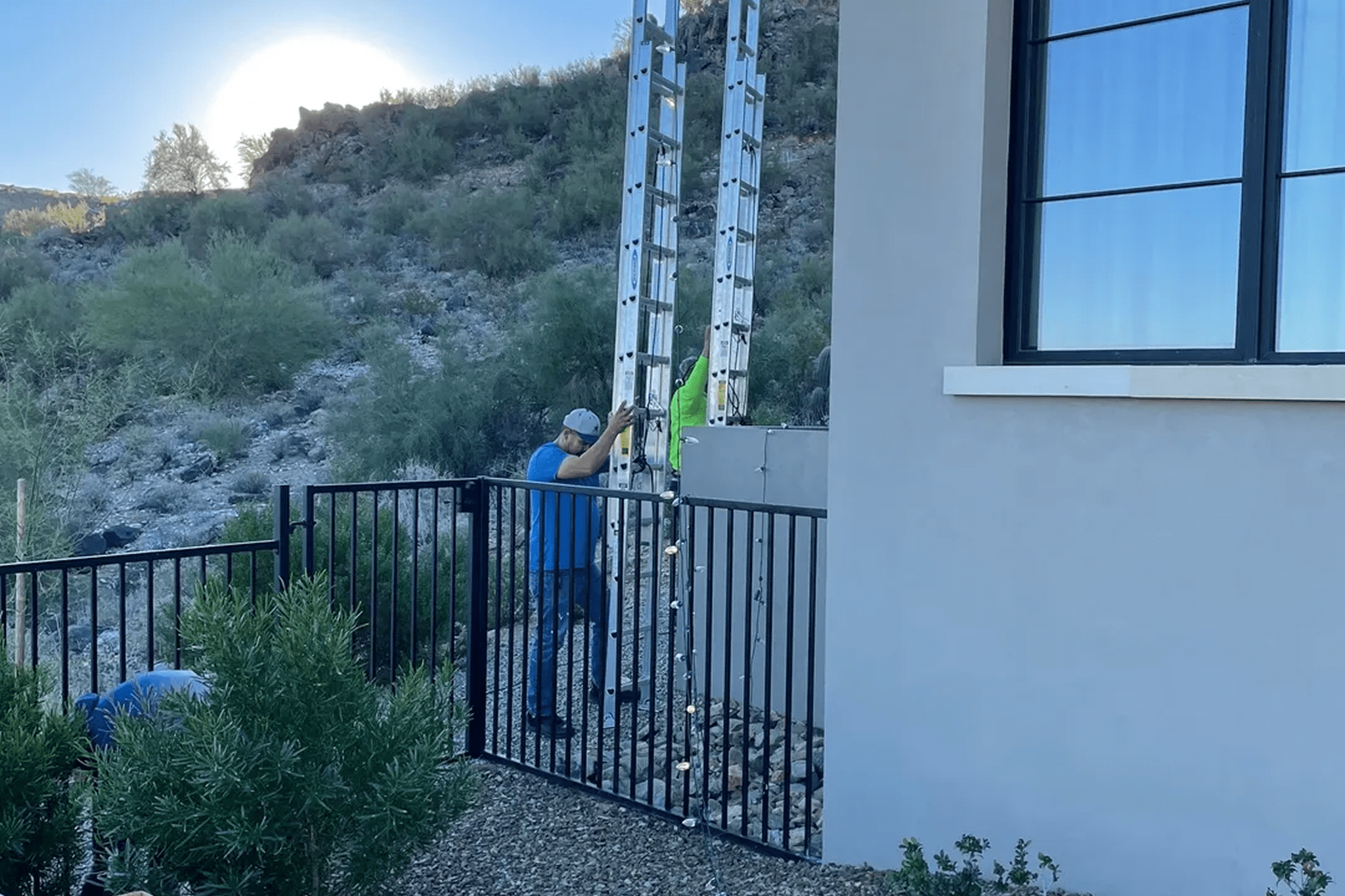 Two workers raising ladder beside house